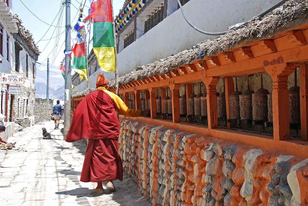 208 Monk Spins Prayer Wheels Near Northern End Of Kagbeni There is a long prayer wheel wall approaching the northern end of Kagbeni, with the restricted region of Upper Mustang beyond.